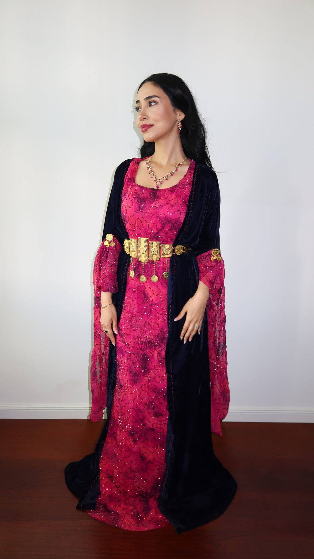 Woman wearing a traditional outfit with a pink top and black skirt against a white background