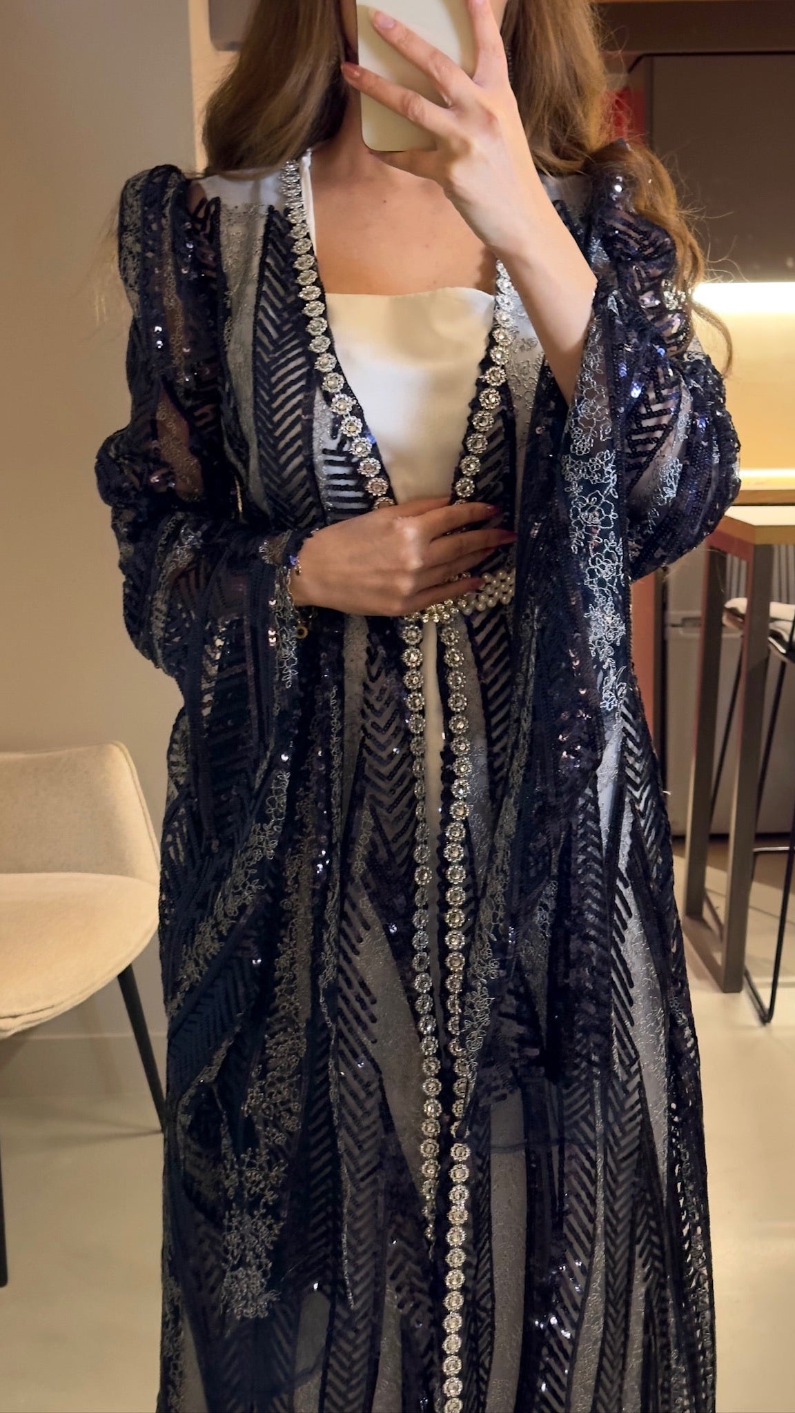 Person wearing a long, dark blue embroidered dress in an indoor setting.